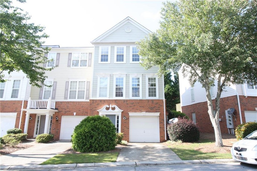 View of front facade featuring a balcony, an attached garage, driveway, and brick siding