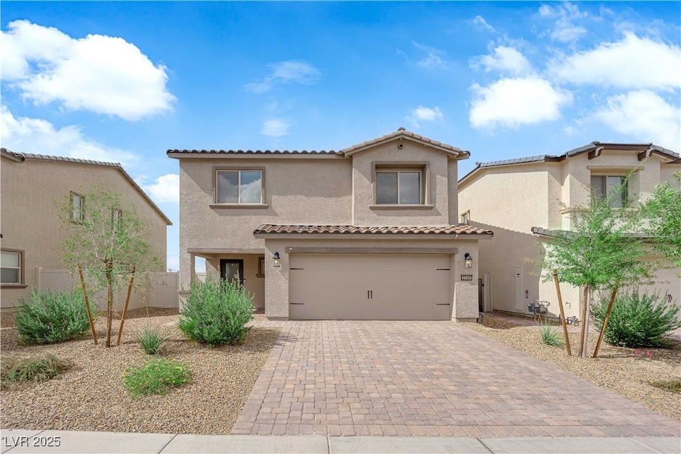 home featuring stucco siding, decorative driveway, a tile roof, and a garage