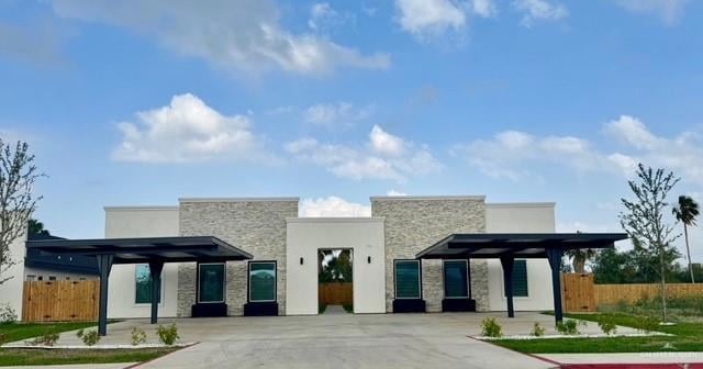 View of front of home featuring stone siding, fence, and stucco siding