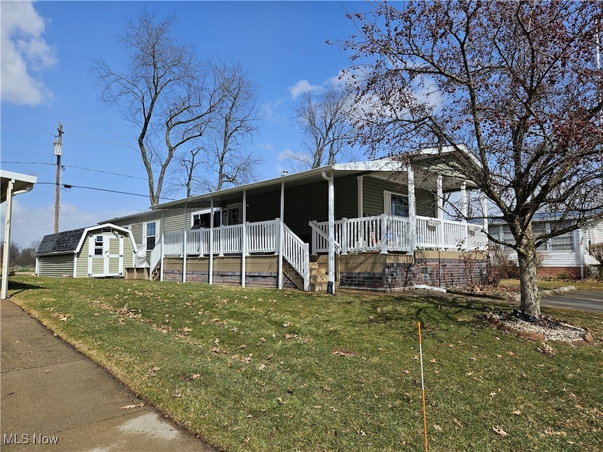 Manufactured / mobile home featuring a storage shed, a front lawn, a porch, and an outdoor structure