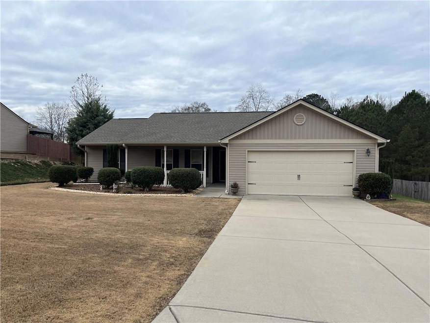 Ranch-style home with covered porch, driveway, a f