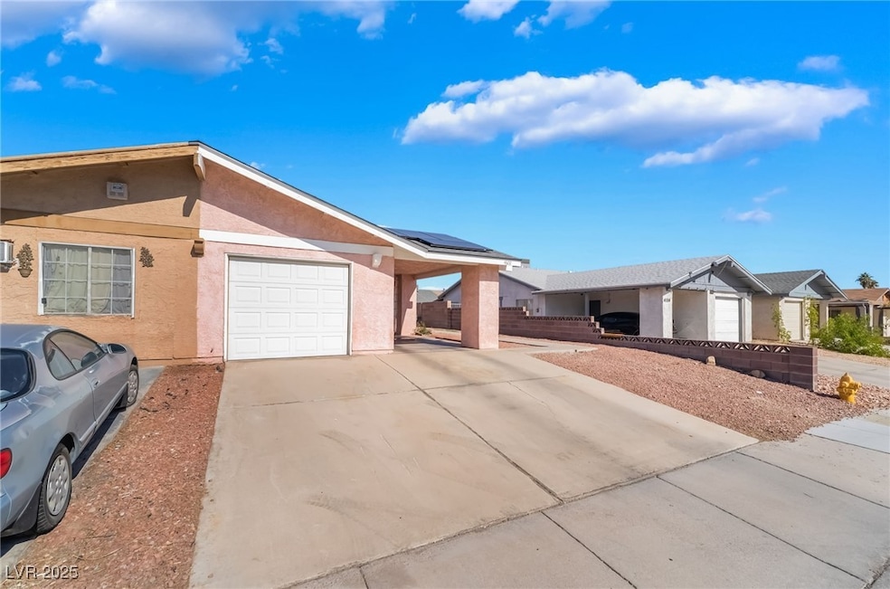 Ranch-style house featuring stucco siding, an attached garage, concrete driveway, and solar panels