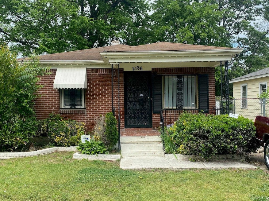 View of front of house with brick siding, a front yard, and fence