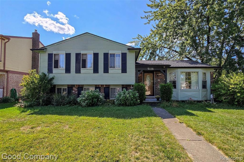 Split level home featuring a front yard and brick siding