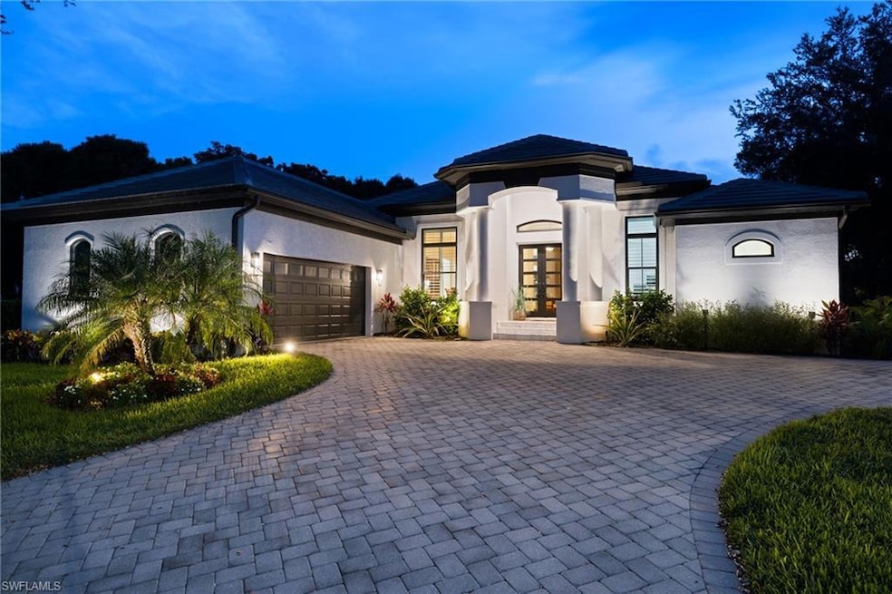 View of front facade with french doors, an attached garage, stucco siding, and decorative driveway