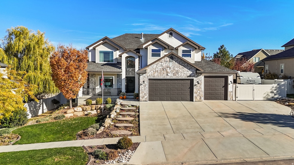 View of front of home featuring a gate, concrete driveway, stone siding, and stucco siding