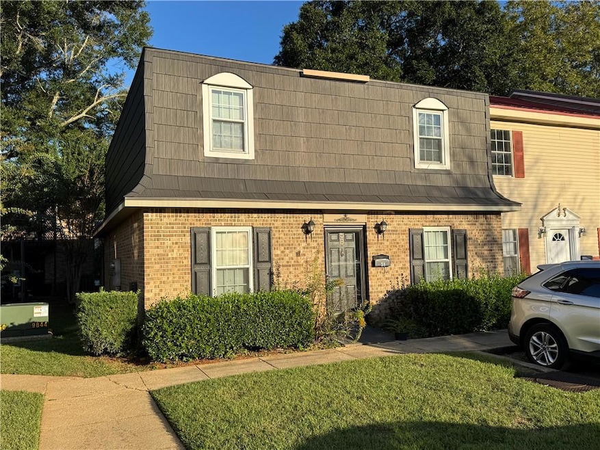 View of front of house featuring brick siding, a front yard, and mansard roof