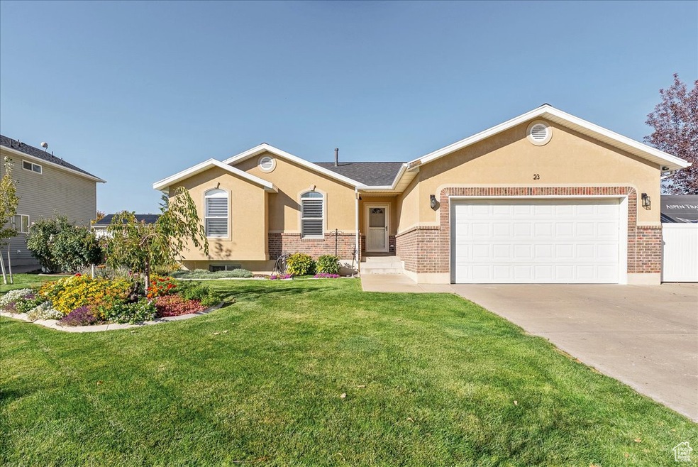 Ranch-style home with a front yard, stucco siding, driveway, and brick siding