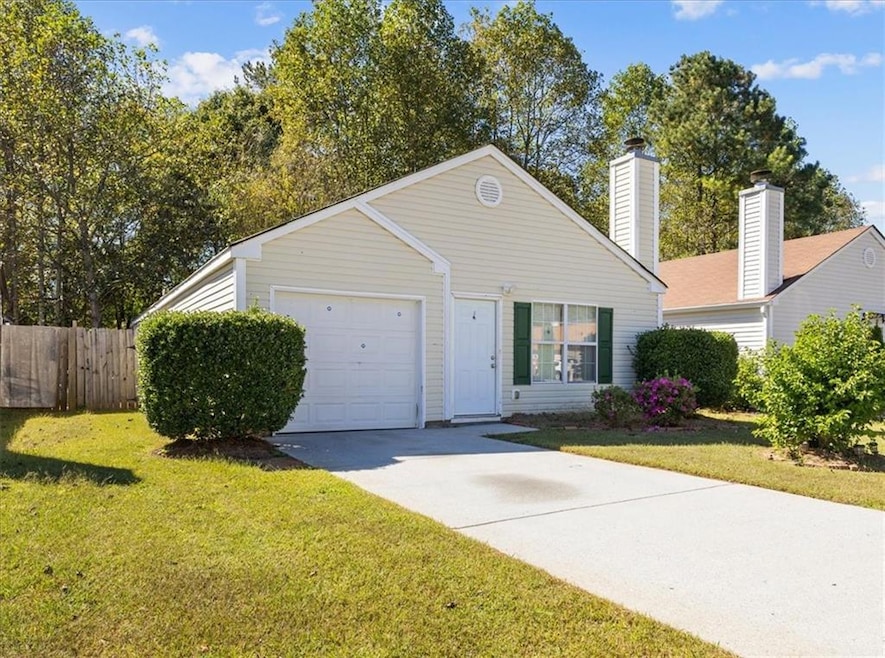 View of front facade with concrete driveway, a chimney, and a garage