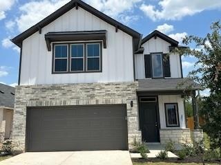 View of front of house with stone siding, drivewa