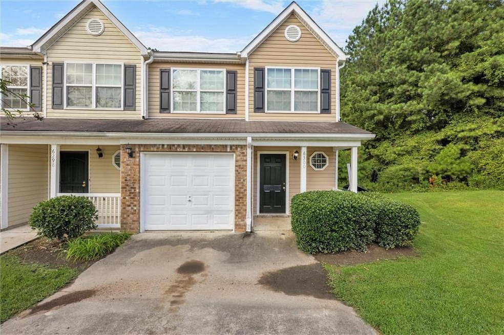 Traditional home featuring a porch, a garage, a front lawn, and brick siding