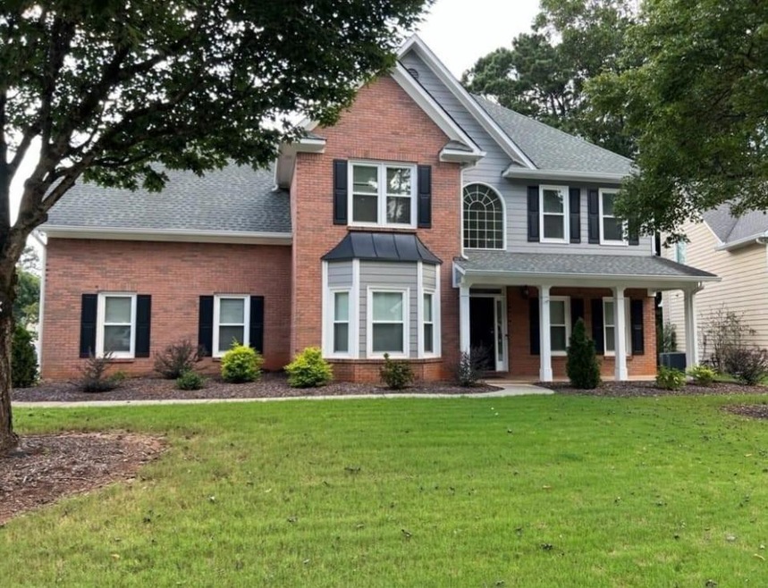 View of front of home with a front lawn, covered p