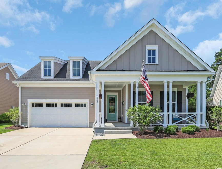 View of front facade featuring board and batten siding, covered porch, an attached garage, a front yard, and concrete driveway