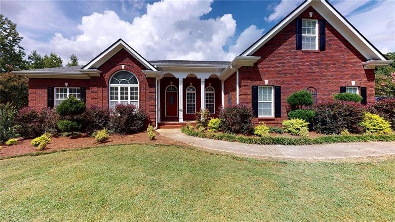 Large 3-sided brick home sits far back from road.