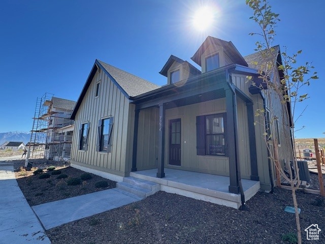 View of front of house with board and batten siding, covered porch, a shingled roof, and a mountain view
