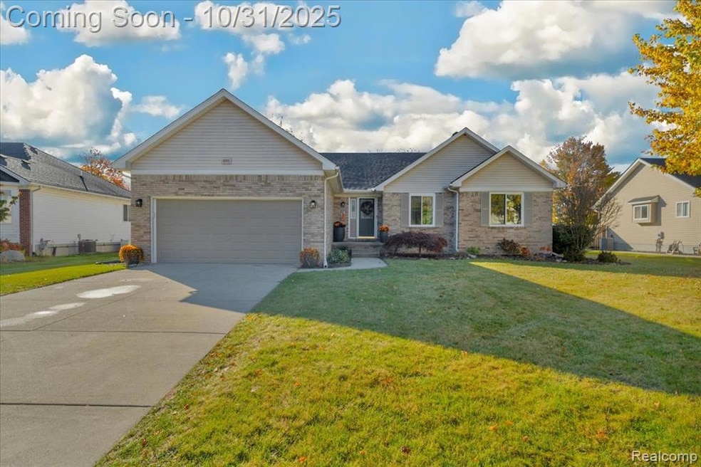 Ranch-style home featuring concrete driveway, a front yard, an attached garage, and brick siding