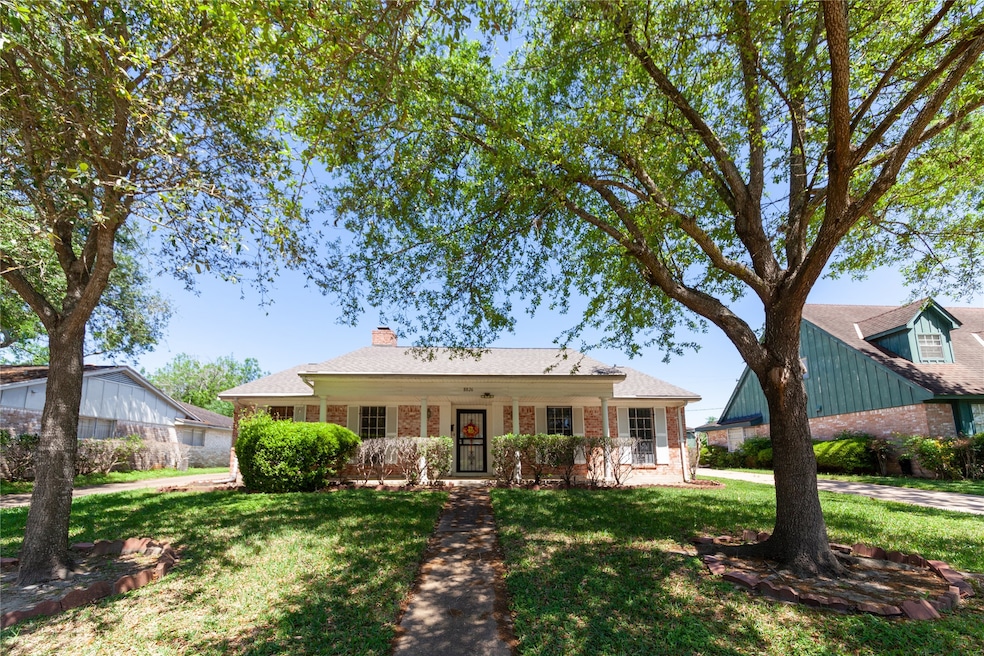 Charming single-story home with a classic brick exterior, nestled between mature trees. It features a welcoming front porch, well-maintained landscaping, and a spacious front yard, offering great curb appeal.