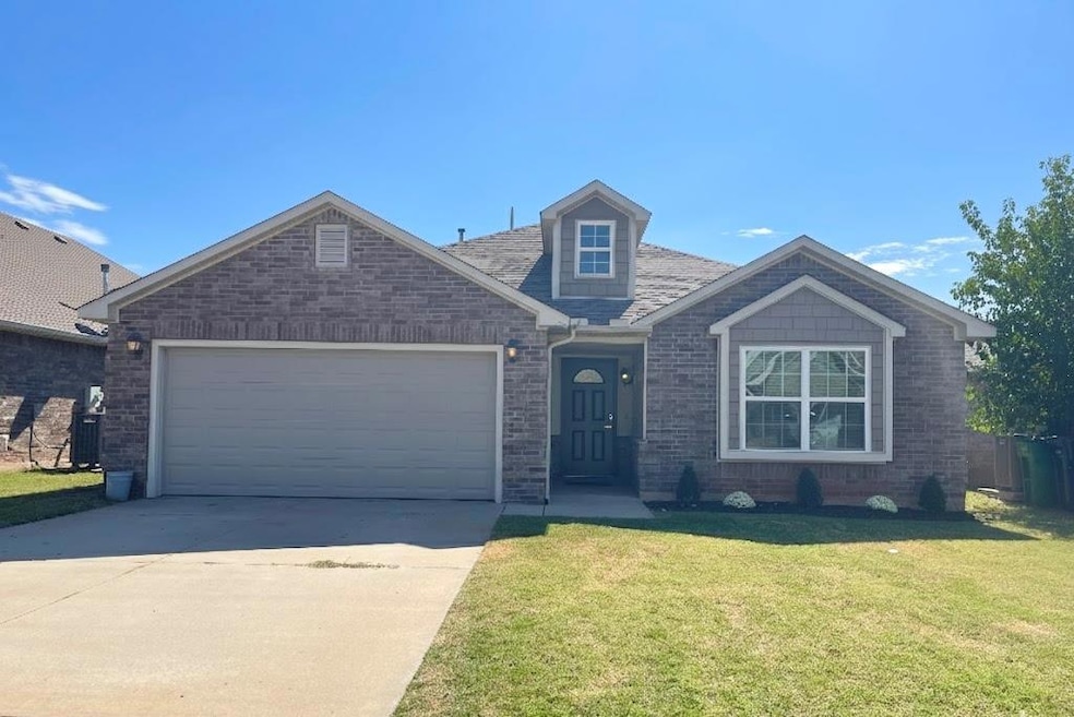 View of front of home featuring a front lawn, concrete driveway, an attached garage, and brick siding