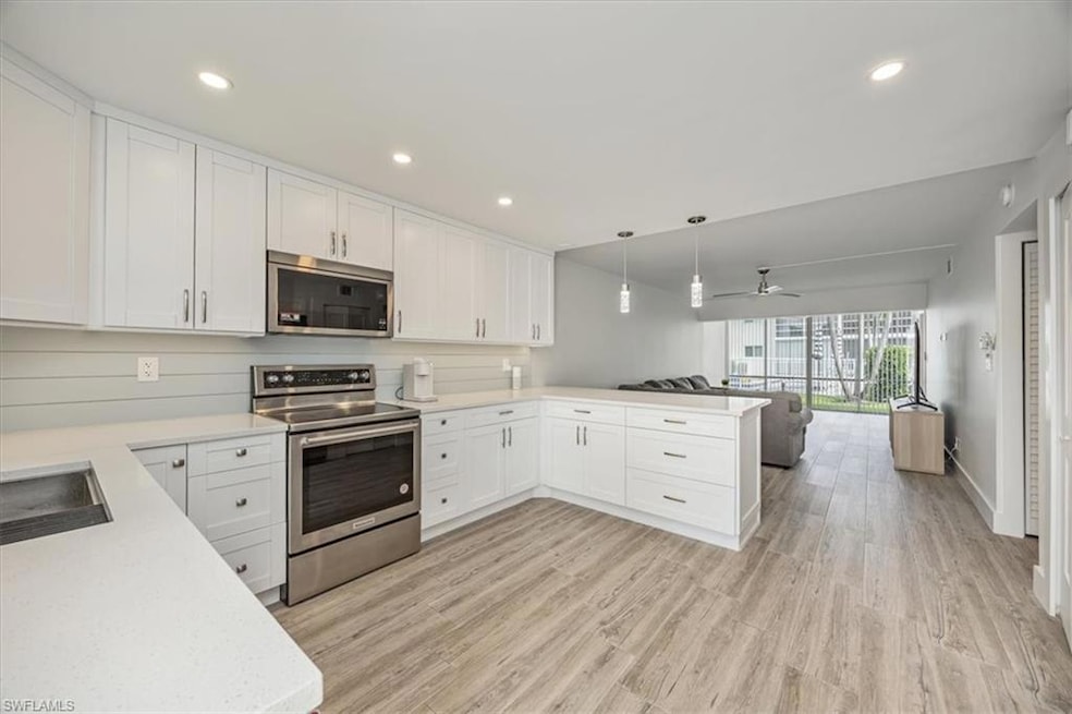 Kitchen with pendant lighting, appliances with stainless steel finishes, white cabinets, and recessed lighting