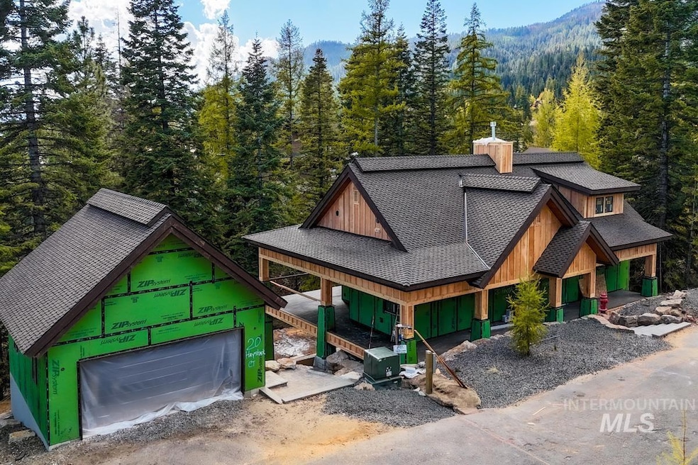 View of front of house featuring an outbuilding, board and batten siding, a porch, a shingled roof, and a wooded view