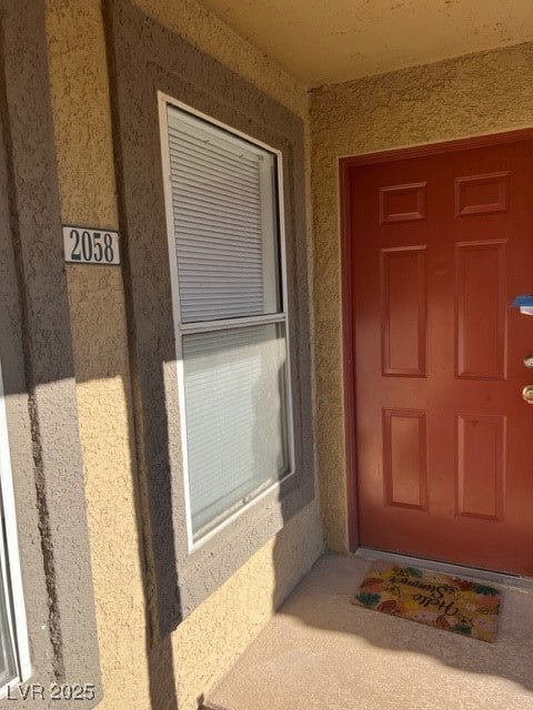 Doorway to property featuring stucco siding