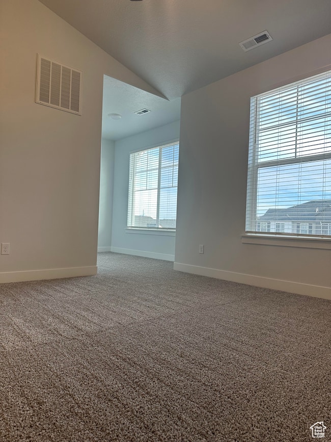 Unfurnished room with light carpet and vaulted ceiling