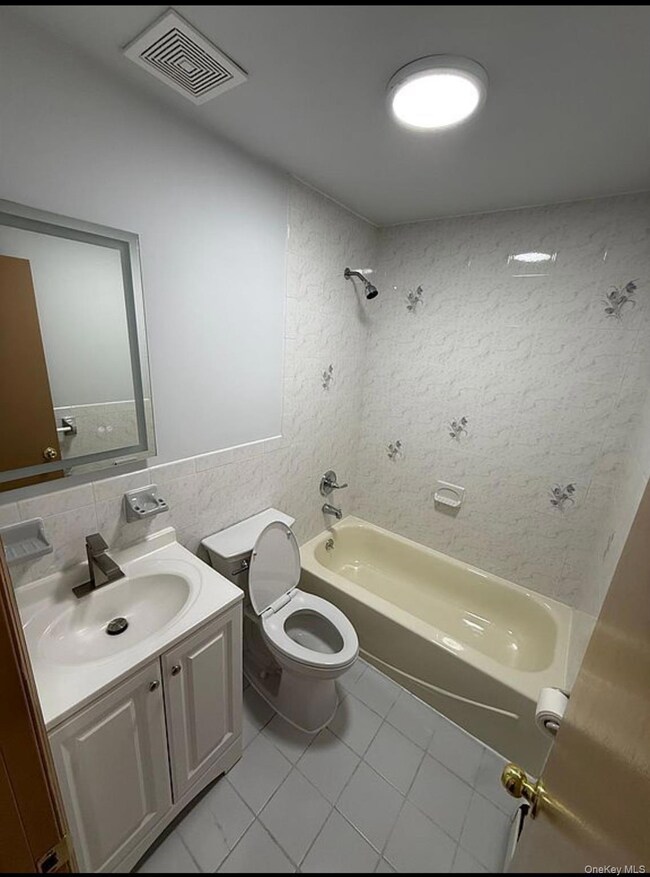 Bathroom featuring vanity, tile walls, shower / tub combination, and light tile patterned floors