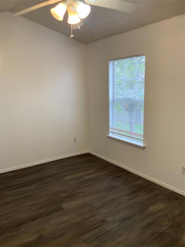 Spare room with a ceiling fan, dark wood-style flo