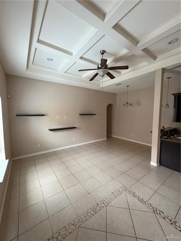 Unfurnished room featuring light tile patterned floors, coffered ceiling, a ceiling fan, arched walkways, and beam ceiling