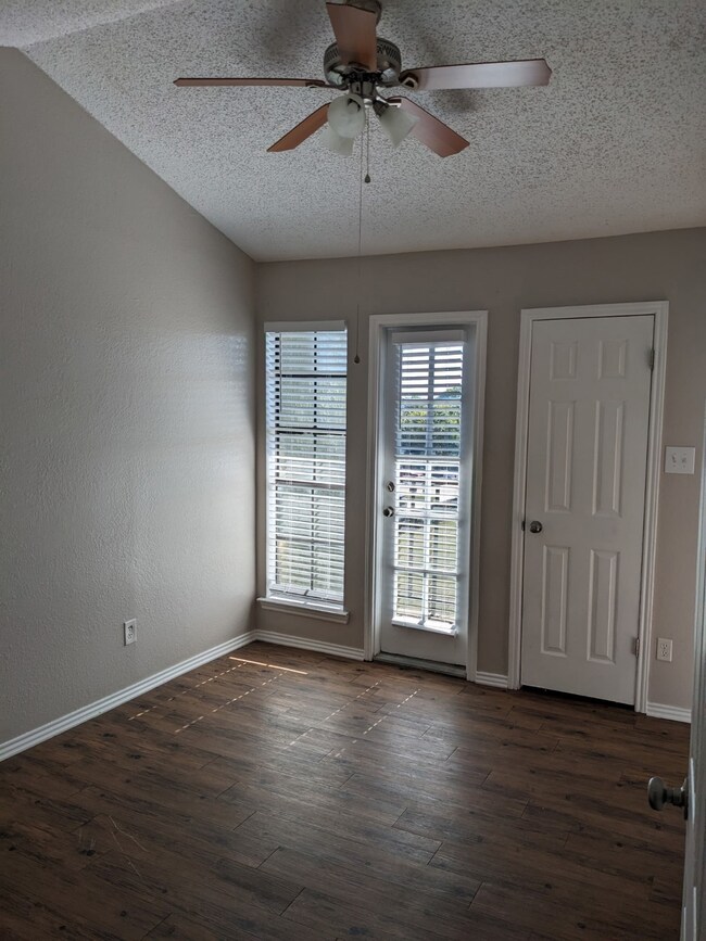 Empty room with a textured ceiling, dark wood-style flooring, and a ceiling fan