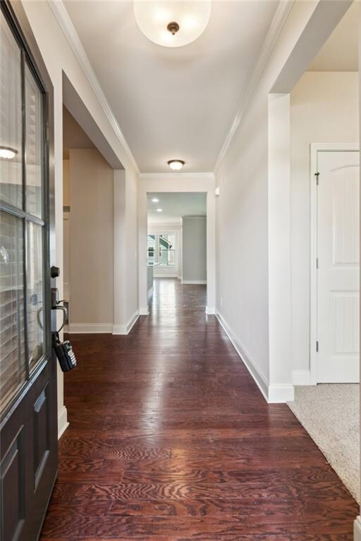Foyer with wood finished floors, ornamental molding, and baseboards