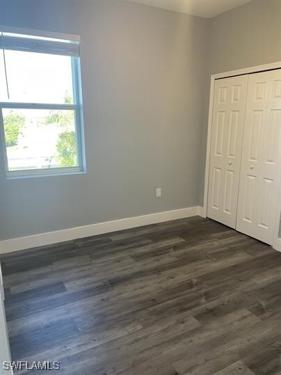 Unfurnished bedroom featuring dark wood-type flooring and a closet
