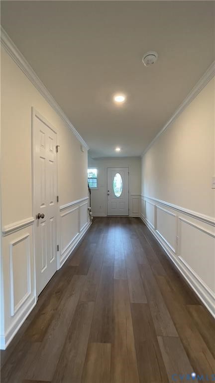 Entryway with ornamental molding, wood finished floors, a decorative wall, and wainscoting