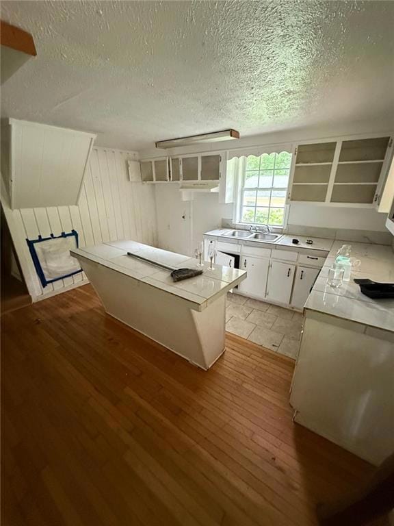 Kitchen featuring light wood-style flooring, open shelves, white cabinetry, light countertops, and a textured ceiling