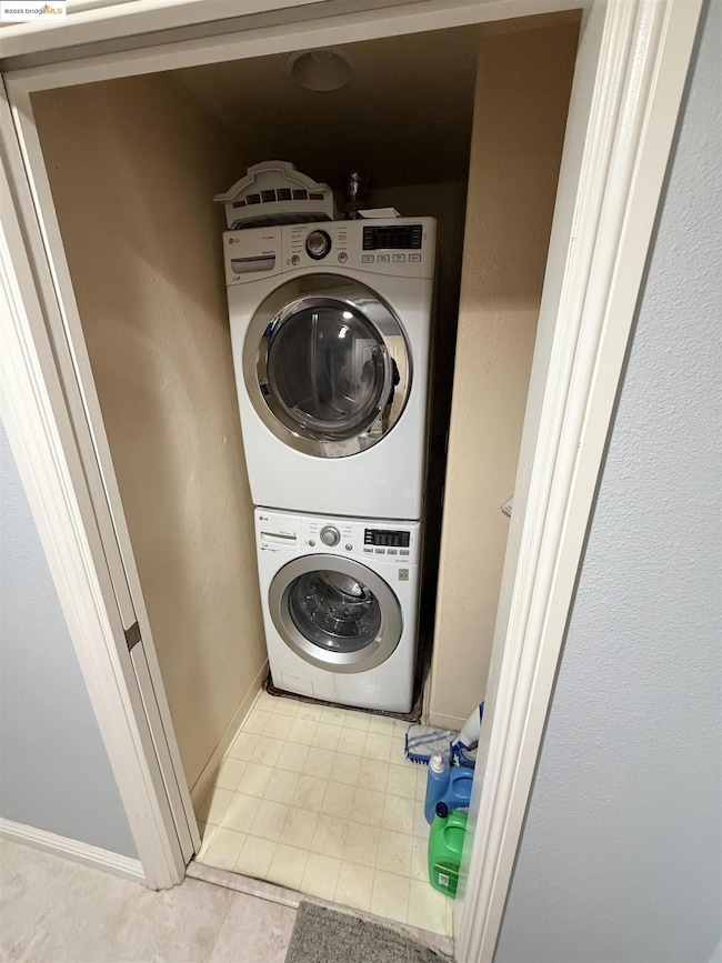 Laundry area with stacked washer / dryer and baseboards