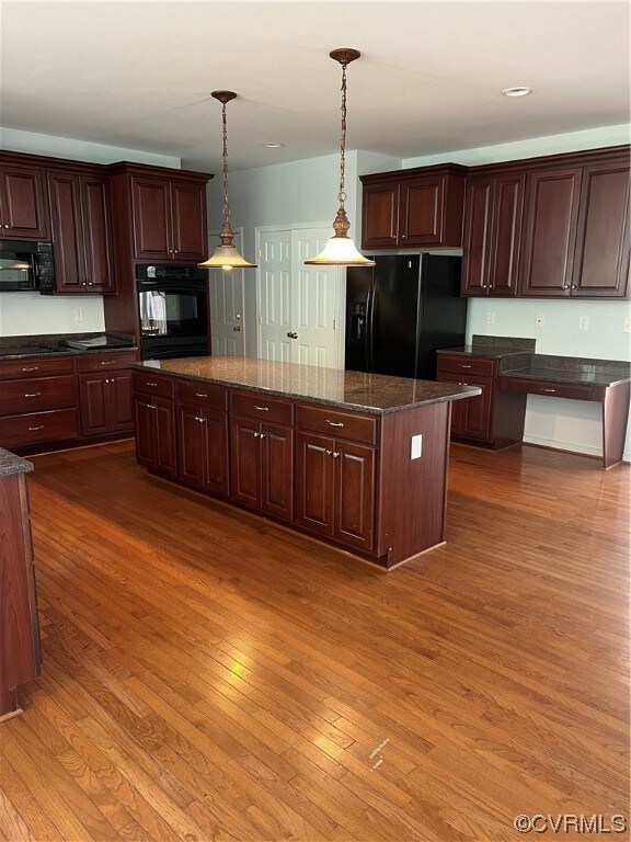 Kitchen featuring decorative light fixtures, fridge, wall oven, dark brown cabinets, and light hardwood floors