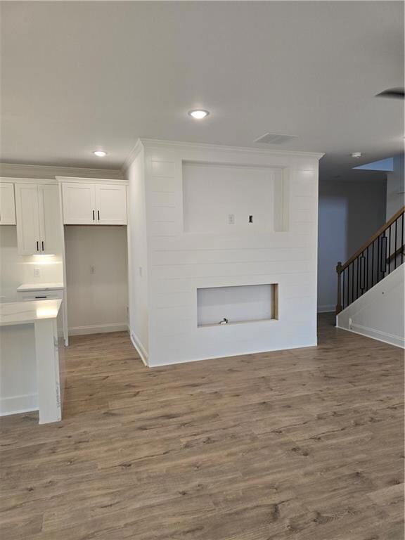 Unfurnished living room featuring light wood-type flooring, stairway, and recessed lighting