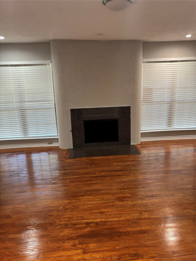 Unfurnished living room featuring a fireplace with flush hearth, dark wood-style floors, and recessed lighting