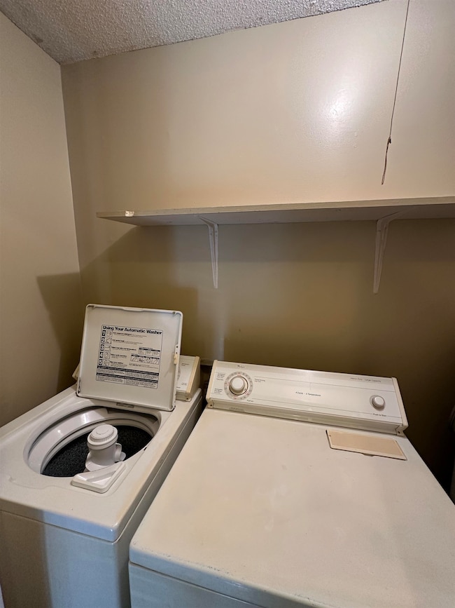 Washroom with washing machine and clothes dryer and a textured ceiling