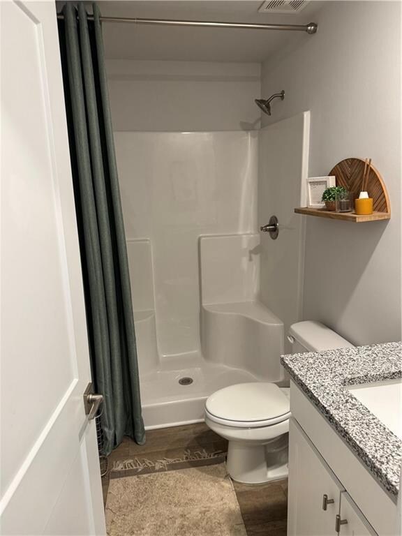 Full bath featuring visible vents, toilet, a showe