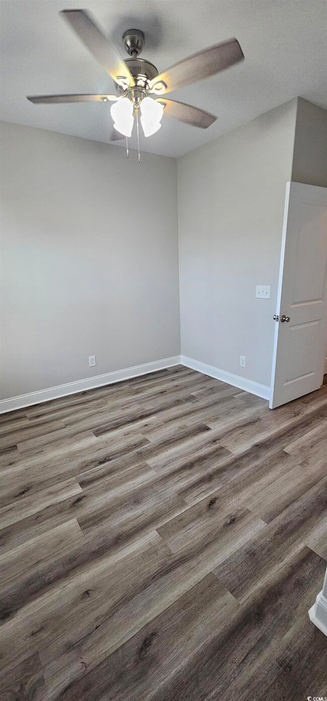 Empty room featuring a ceiling fan and dark wood finished floors