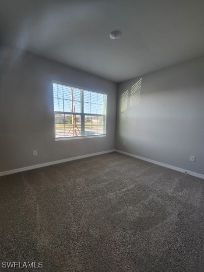 Unfurnished room with baseboards and dark colored