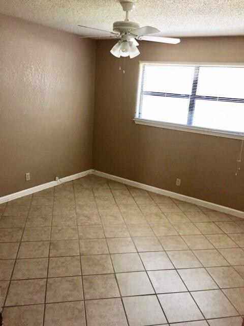 Unfurnished room with a textured ceiling, light tile patterned floors, and ceiling fan