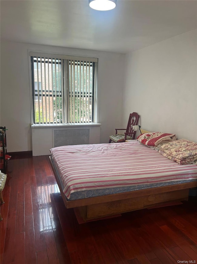 Bedroom featuring radiator, multiple windows, and hardwood / wood-style flooring