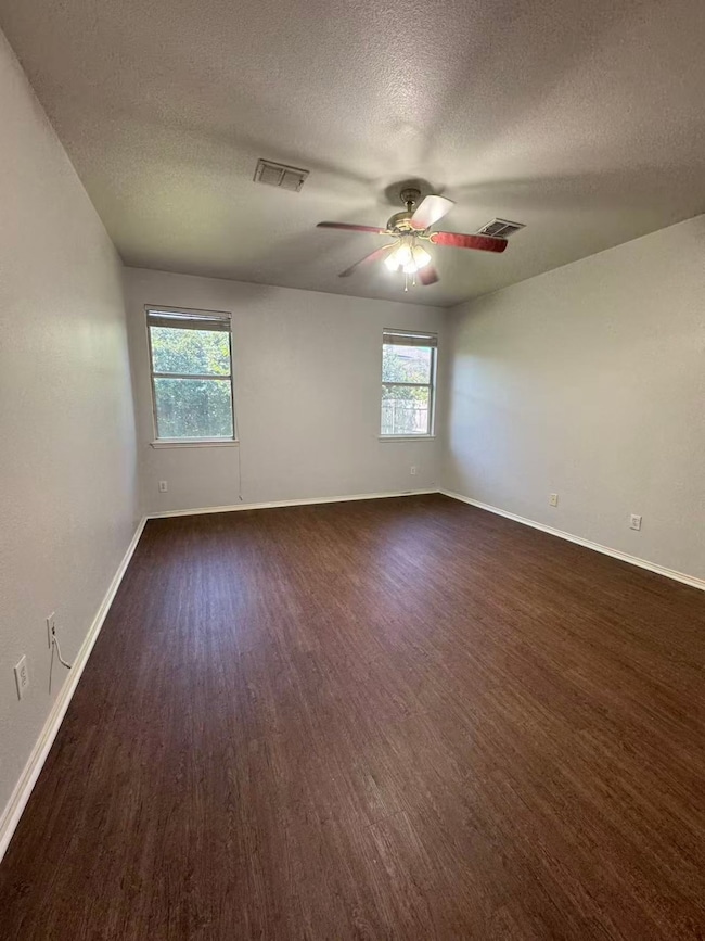 Unfurnished room with a textured ceiling and dark wood-type flooring