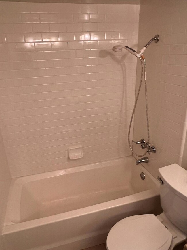 Bathroom with tiled shower / bath combo and toilet