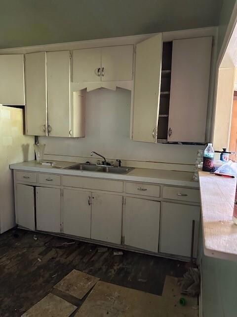 Kitchen featuring dark tile flooring, white cabinets, and sink