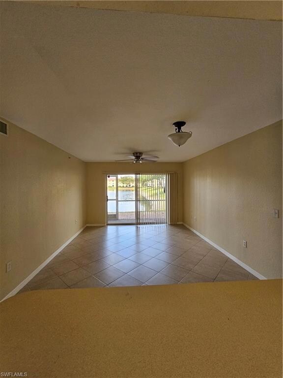 Spare room with a ceiling fan, carpet, baseboards, and a textured ceiling
