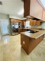 Kitchen with a peninsula, brown cabinets, stainless steel fridge with ice dispenser, light countertops, and black electric stovetop
