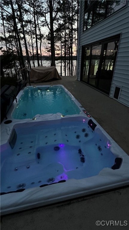 Outdoor pool featuring an outdoor hot tub and a water view
